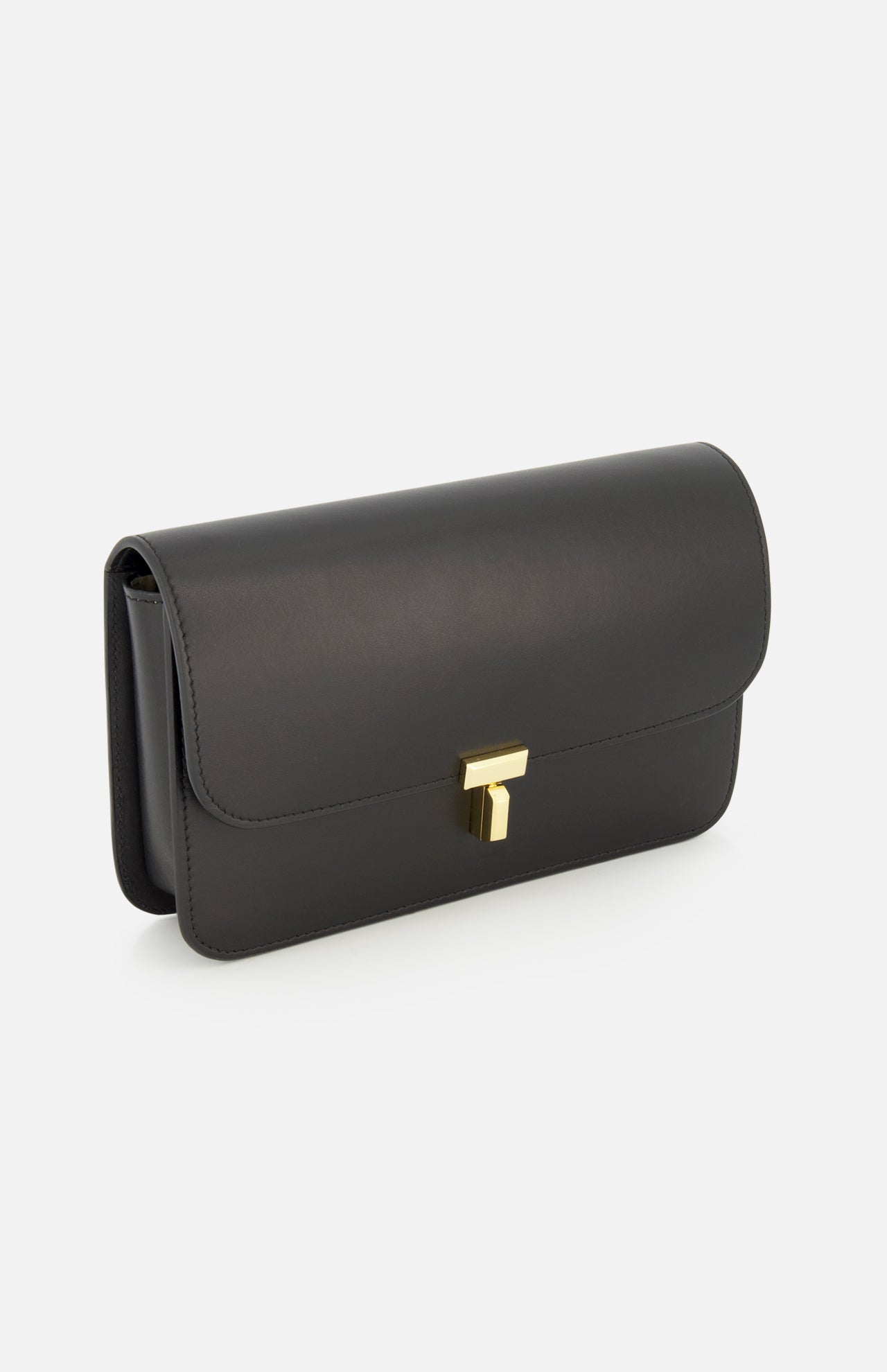 The TOTEME T-Lock Leather Crossbody Bag, featuring a sleek black leather finish and a gold rectangular clasp, is photographed on a white background, capturing the refined elegance of a sculptural silhouette and exuding the timeless sophistication of Italian-made accessories.