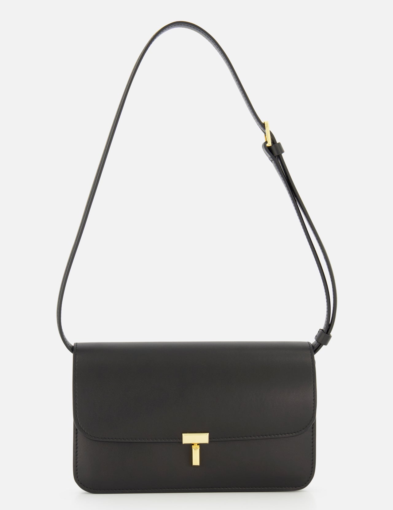 The TOTEME T-Lock Leather Crossbody Bag is a sculptural shoulder bag crafted from black leather in Italy, featuring a gold T-shaped clasp and an adjustable strap, displayed against a plain white background.