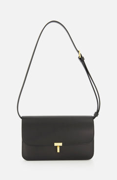 The TOTEME T-Lock Leather Crossbody Bag is a sculptural shoulder bag crafted from black leather in Italy, featuring a gold T-shaped clasp and an adjustable strap, displayed against a plain white background.