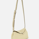 The TOTEME T-Lock Rope Clutch is a beige textured shoulder bag with an artisanal rope detail, long adjustable strap, silver buckle, and flap closure, shown on a plain white background.
