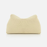 The TOTEME T-Lock Rope Clutch is a cream sculptural bag featuring a textured wave pattern and soft, structured shape, shown against a plain white background.