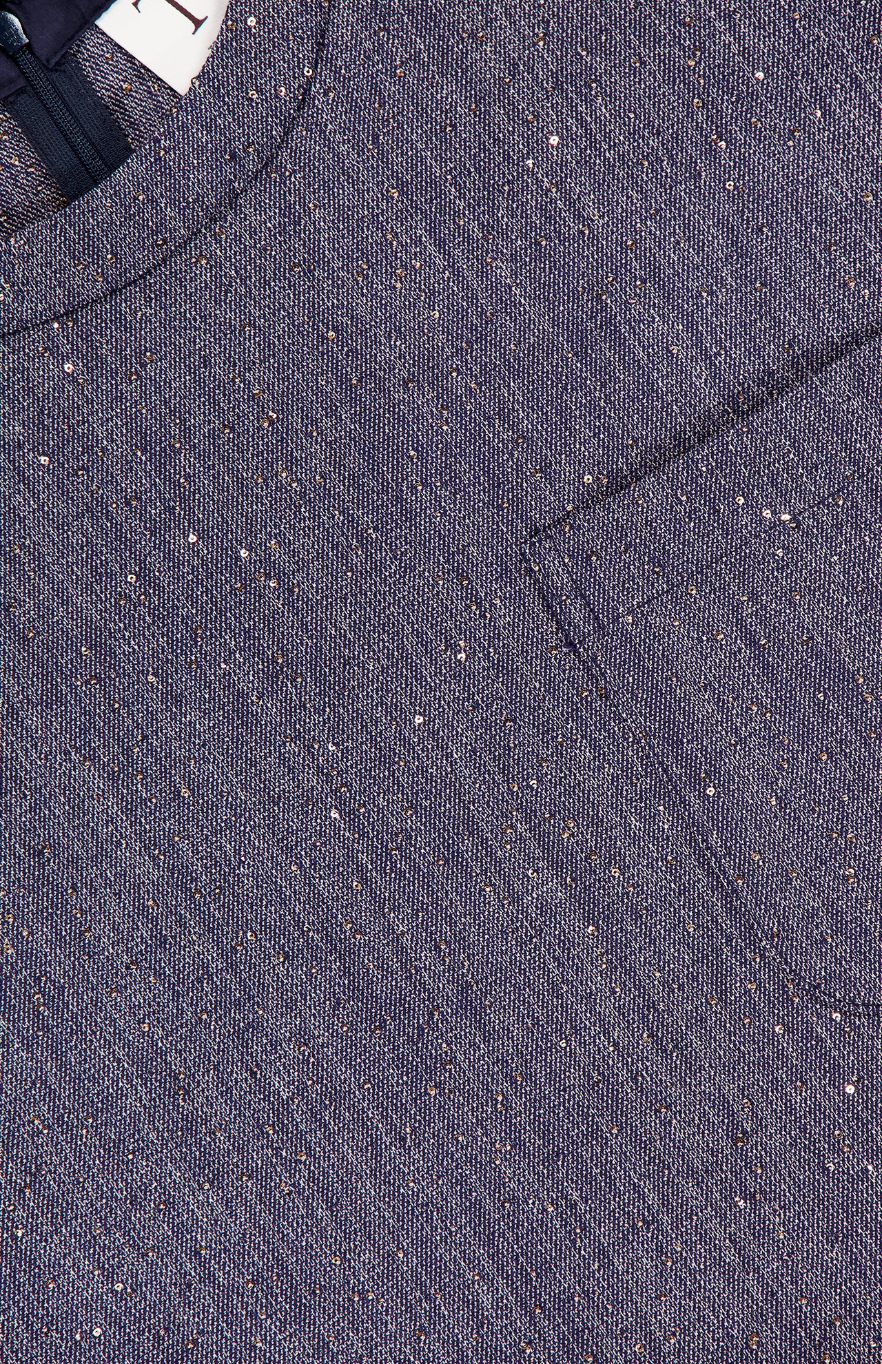 Close-up of the TWP Ex Cropped Sequin Denim T Shirt reveals blue textured fabric with speckled details, a round neckline, chest pocket, and cropped boxy silhouette—hallmarks of modern women's workwear.