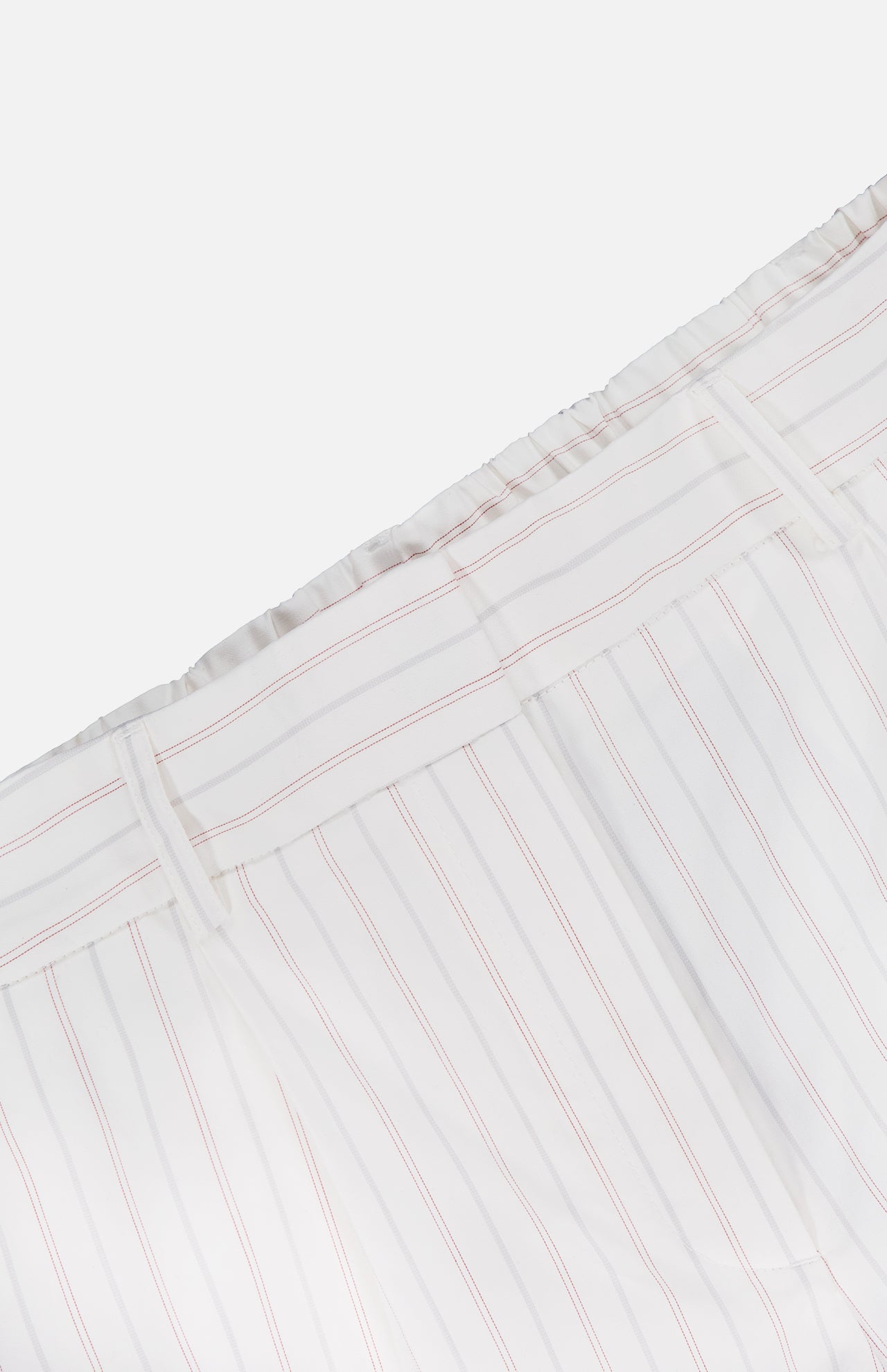 Close-up of TWP's Hudson St Trouser Pant, white with thin vertical pink stripes, featuring an elasticized waist and belt loops, shown against a white background.