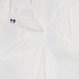 The Hudson St Trouser Pant by TWP features white fabric with thin light red vertical pinstripes. These relaxed pants are styled unbuttoned and partially unzipped, showing the inside waistband and button details.