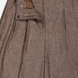 The Avery Wide Leg Trouser Pant by TWP showcases classic brown herringbone wool with pleats, featuring a partially unzipped and unbuttoned waistband that reveals the front closure and inner lining. These wide-leg trousers offer a refined workwear silhouette for women.