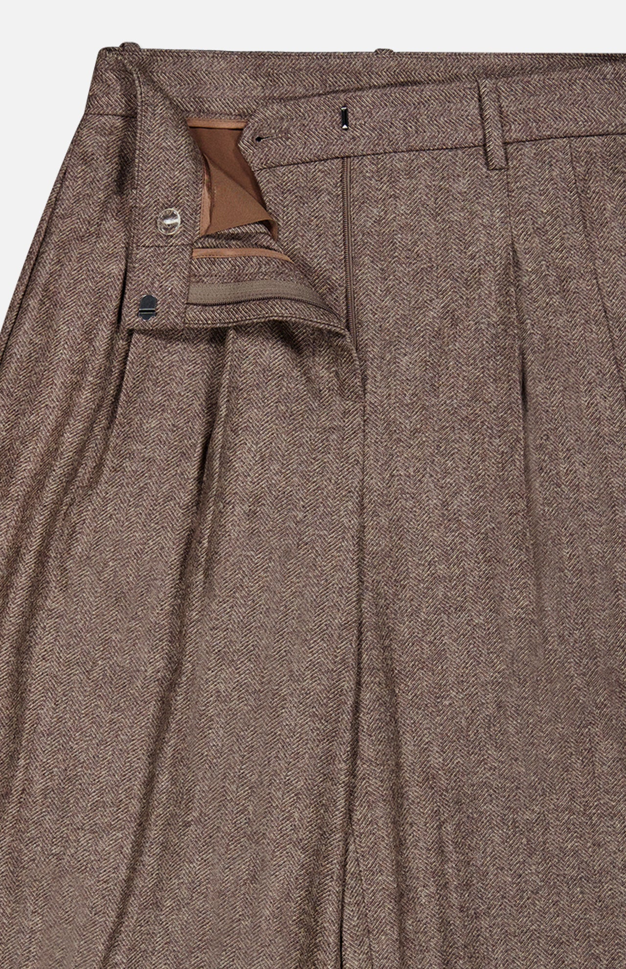 The Avery Wide Leg Trouser Pant by TWP showcases classic brown herringbone wool with pleats, featuring a partially unzipped and unbuttoned waistband that reveals the front closure and inner lining. These wide-leg trousers offer a refined workwear silhouette for women.