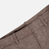 Close-up of the waistband and pleats of the Avery Wide Leg Trouser Pant by TWP in a brown herringbone pattern, highlighting the belt loops and rich fabric texture against a plain white background. These wide-leg trousers offer a sophisticated touch to women’s workwear.