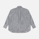 The TWP Big Joe Glossy Stripe Shirt shown flat with the back facing up reveals its yoke and pleat details. This oversized, light gray button-up features long sleeves and is displayed on a plain white background.