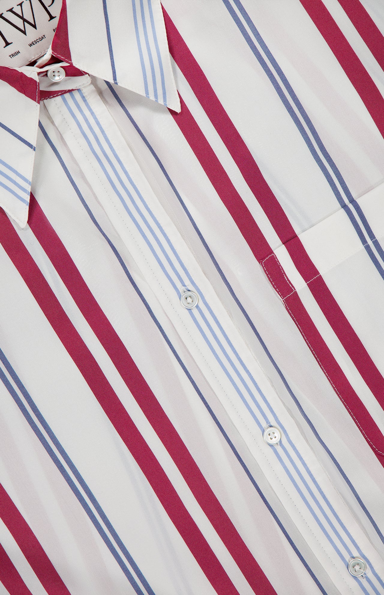 Close-up of the TWP Big Joe Oversized Shirt, featuring red and light blue vertical stripes on white, a chest pocket, and a pointed collar.