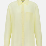 The TWP Big Joe Oversized Shirt is a light yellow, long-sleeved top made from a cotton silk blend, featuring a collar and chest pocket, shown against a plain white background.