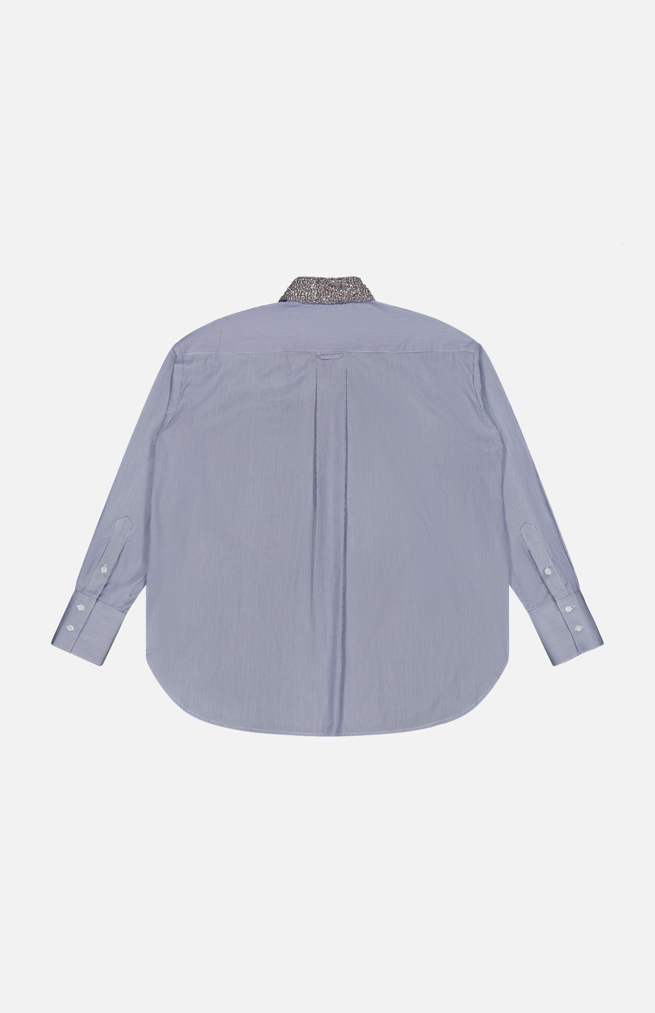 The TWP Big Joe with Crystal Collar Shirt is displayed from the back in light blue, featuring a curved hem and white cuff buttons. The collar stands out with a dark crystal-patterned design, adding a unique detail to this women’s workwear shirt against a plain white background.