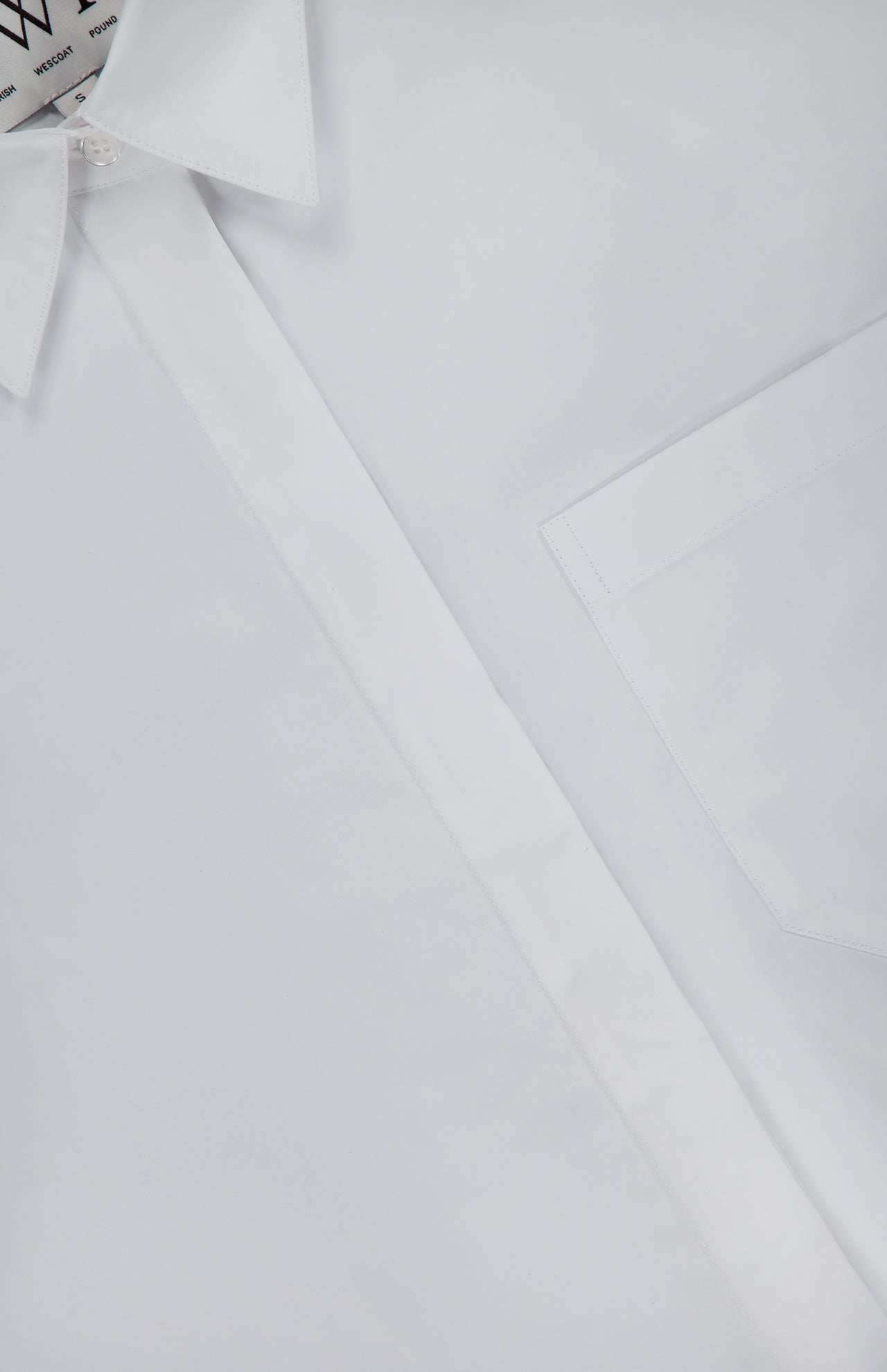 Close-up of TWP's Cowboy Update Relaxed Fit Shirt—a crisp, white button-down with a pointed collar and chest pocket, neatly pressed and lying flat—a timeless staple in women’s workwear.