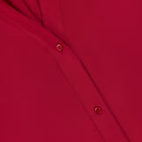 Close-up of TWP's Deep V Relaxed Shirt in red Italian superfine cotton, highlighting two paneled seams and three red buttons. The smooth, neatly stitched fabric suggests refined workwear with a relaxed fit for women.