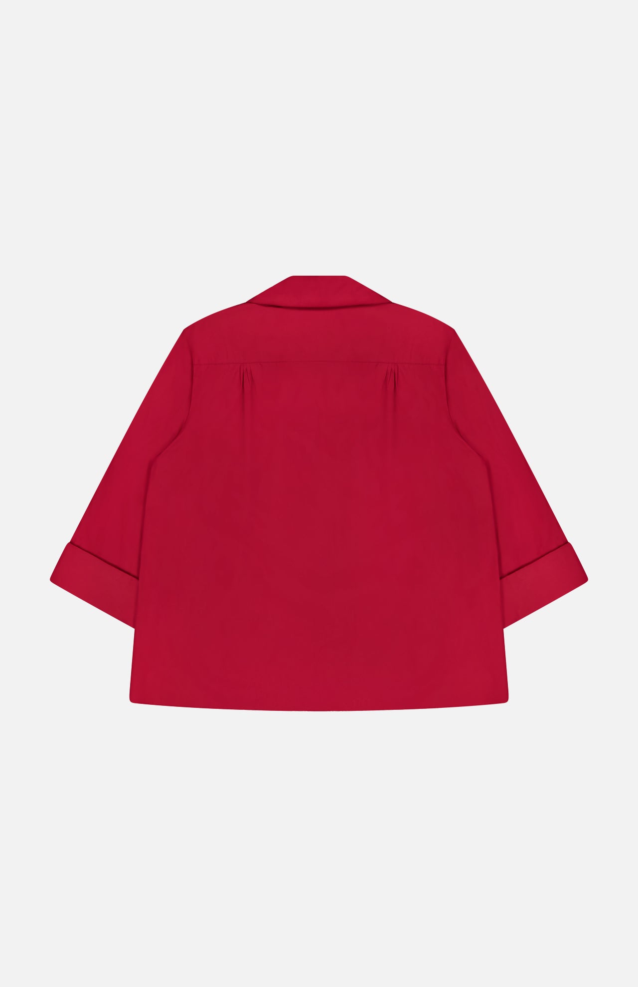 The TWP Deep V Relaxed Shirt, shown from the back in bright red, features a loose fit, long sleeves with folded cuffs, and a straight hem. Made from Italian superfine cotton and set against a plain white background.