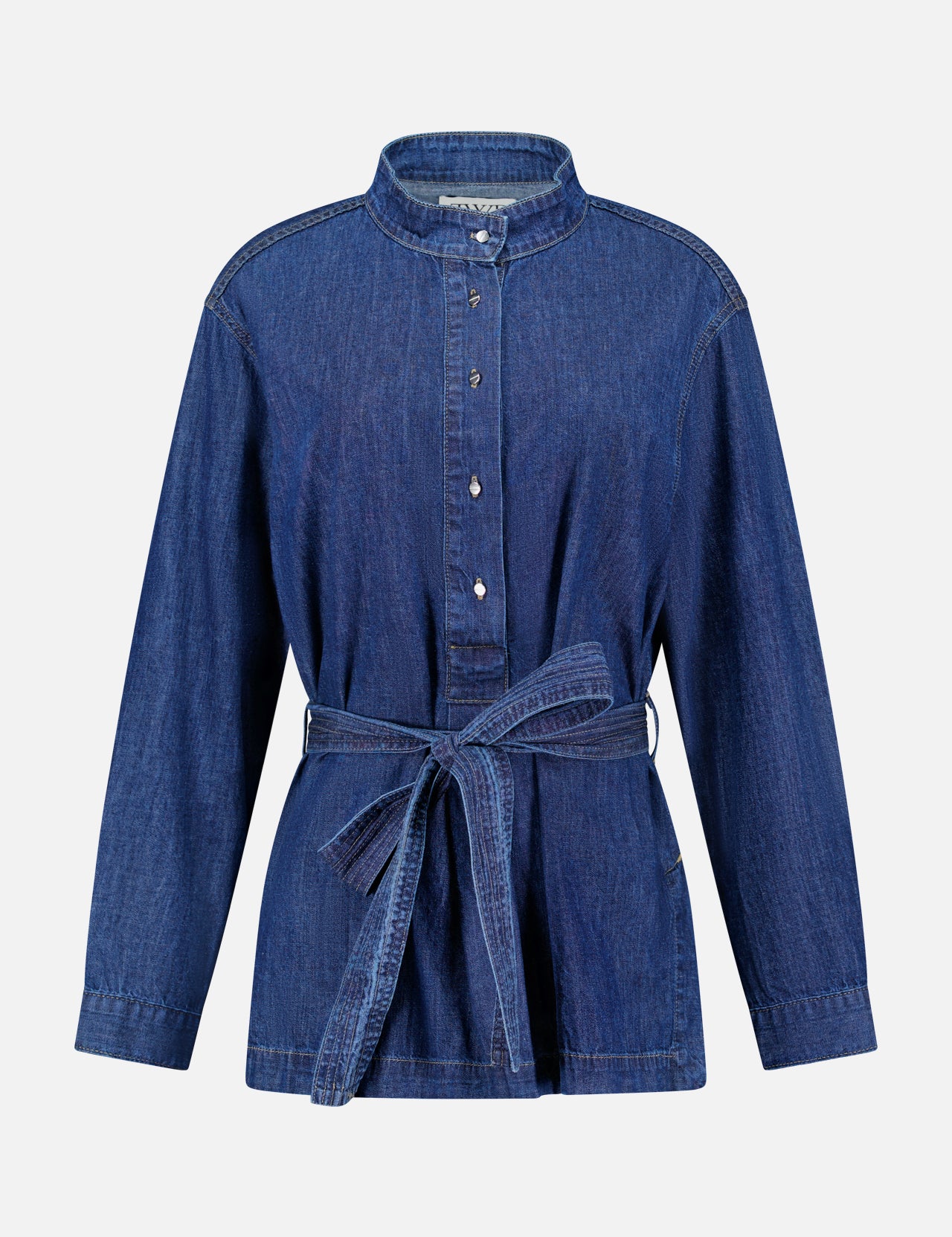 The Denim Tamzin Wrap Shirt by TWP is a long-sleeve blue denim button-up featuring a stand collar and a matching denim waist belt, shown against a plain white background—ideal for versatile women’s workwear or styled as a chic belted wrap jacket.