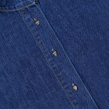 Close-up of the TWP Denim Tamzin Wrap Shirt in blue denim, showcasing a round collar, signature white TWP label, and silver snap buttons down the front—an effortless twist on classic women’s workwear.