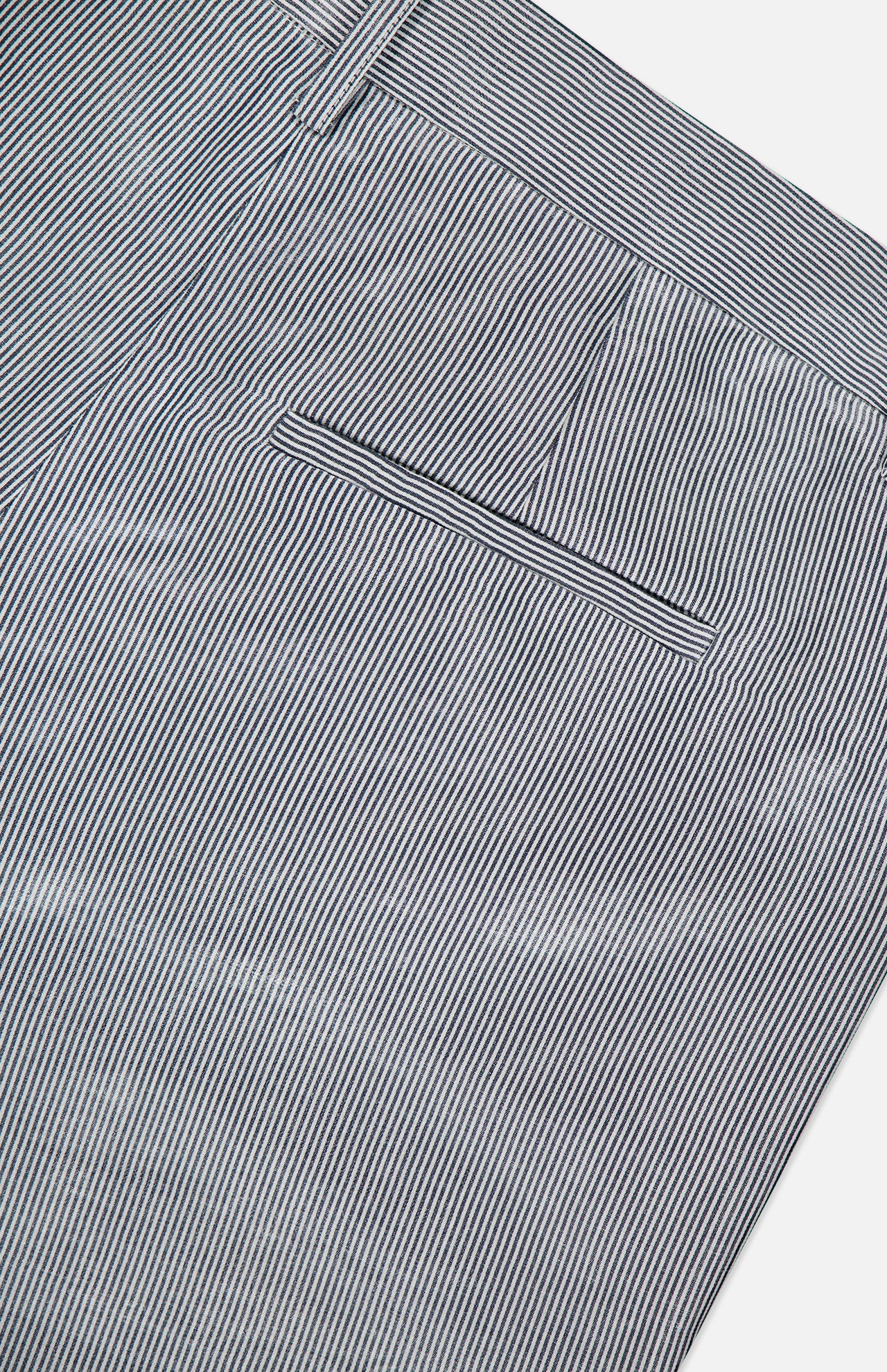 Close-up of the back pocket and waistband of TWP's Dillon Glossy Stripe Pants, featuring thin vertical light blue and white stripes and a neatly sewn pocket—an elevated, modern twist on classic women's workwear.