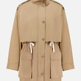 The Drawing Conclusions Jacket by TWP is a beige chino twill utility trench coat designed for women, featuring large front pockets, an adjustable waist drawstring, button-down front, and a high collar. This relaxed-fit workwear staple is finished with shoulder epaulets for a timeless utilitarian flair.
