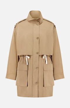 The Drawing Conclusions Jacket by TWP is a beige chino twill utility trench coat designed for women, featuring large front pockets, an adjustable waist drawstring, button-down front, and a high collar. This relaxed-fit workwear staple is finished with shoulder epaulets for a timeless utilitarian flair.