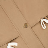 A close-up of the TWP Drawing Conclusions Jacket highlights its beige utility design with brown buttons and white drawstrings, showcasing fabric texture and detailed stitching—a modern take on workwear for women.