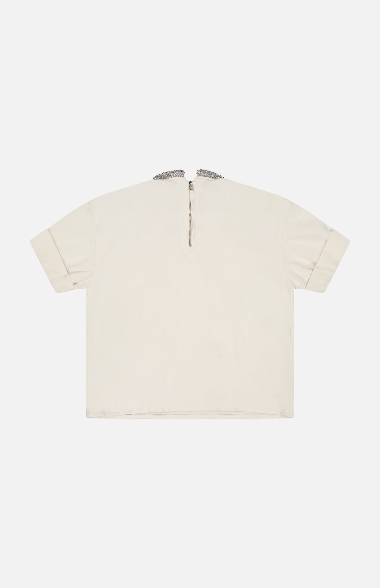 The TWP Ex T Shirt With Crystal Collar is a short-sleeved, off-white cropped cotton top shown laid flat with the back facing up. It features a small top-center zipper near the collar adorned with subtle crystal detailing.