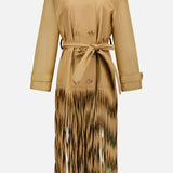 The TWP Fringe Benefit Jacket is a tan, long-sleeve trench coat with a waist belt, double-breasted buttons, and fringe accents below the knees for a stylish women’s workwear look with flowing cut-out details.