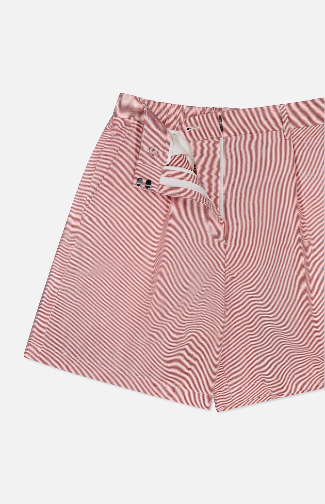 The TWP Henry St Stripe Short features red and white pinstripes, a mid-rise fit, front zipper and button closure, partially unzipped to show the interior waistband and lining—ideal for stylish workwear. Displayed on a white background.