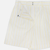 The TWP Henry St Striped Shorts are women's mid-rise, light-colored shorts with yellow vertical stripes and a partially open waistband showing the button and zipper—perfect as stylish workwear.