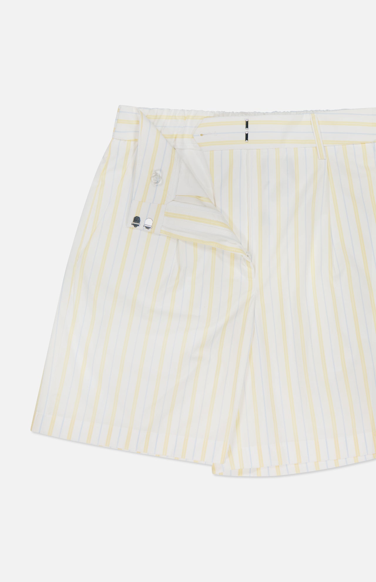 The TWP Henry St Striped Shorts are women's mid-rise, light-colored shorts with yellow vertical stripes and a partially open waistband showing the button and zipper—perfect as stylish workwear.