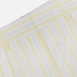 Close-up of TWP's Henry St Striped Shorts, showcasing vertical yellow and light blue stripes on white fabric with an elastic waistband and belt loops.