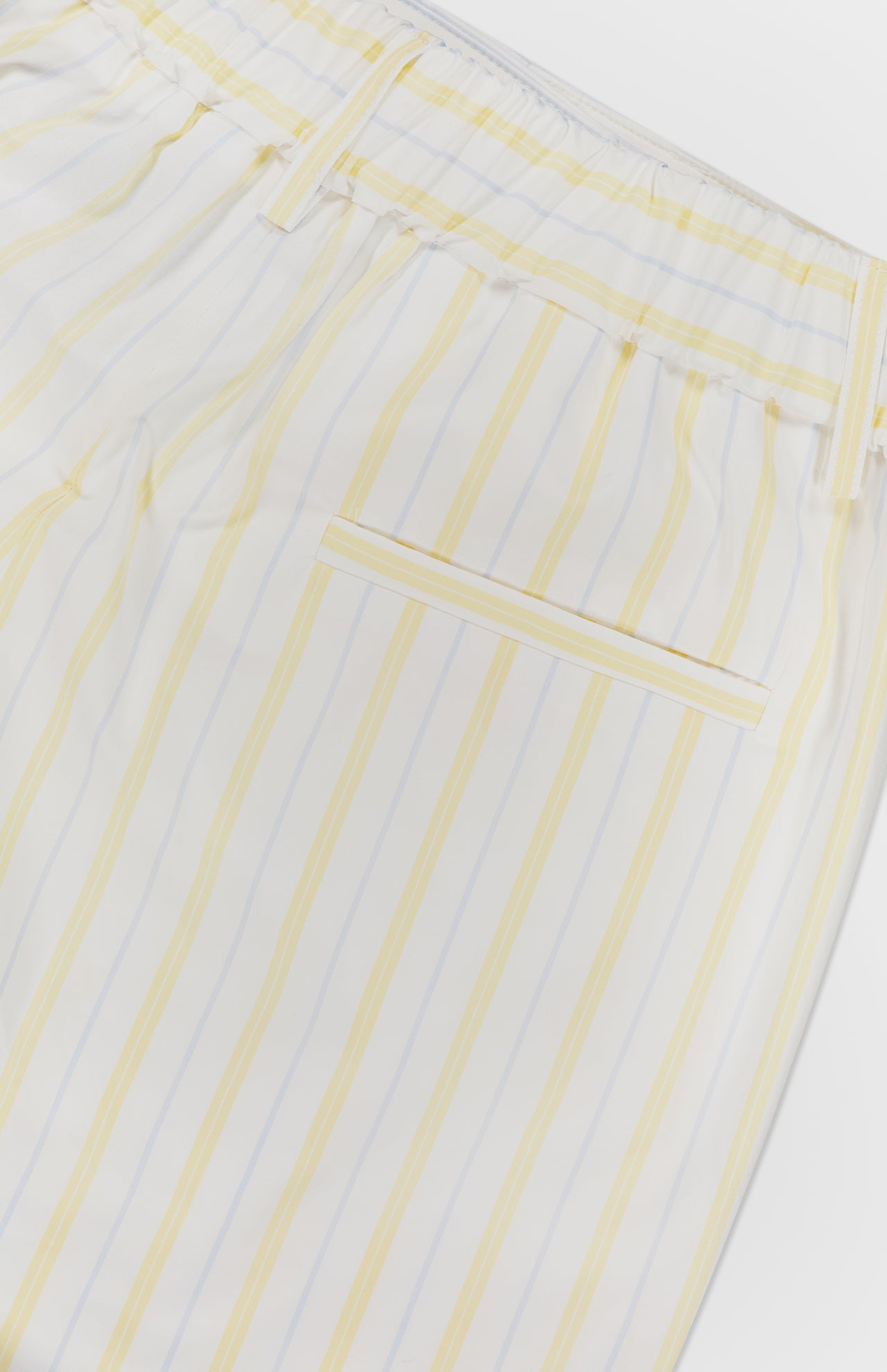The Henry St Striped Shorts by TWP feature white fabric with light yellow and pale blue stripes, an elastic waistband, single back welt pocket, and a relaxed mid-rise fit inspired by women's workwear shorts.
