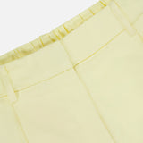 Close-up of the TWP Hudson St Pleated Pant in pale yellow, featuring belt loops, a pleated elastic back waistband, and front seam details—an ideal workwear choice for women.