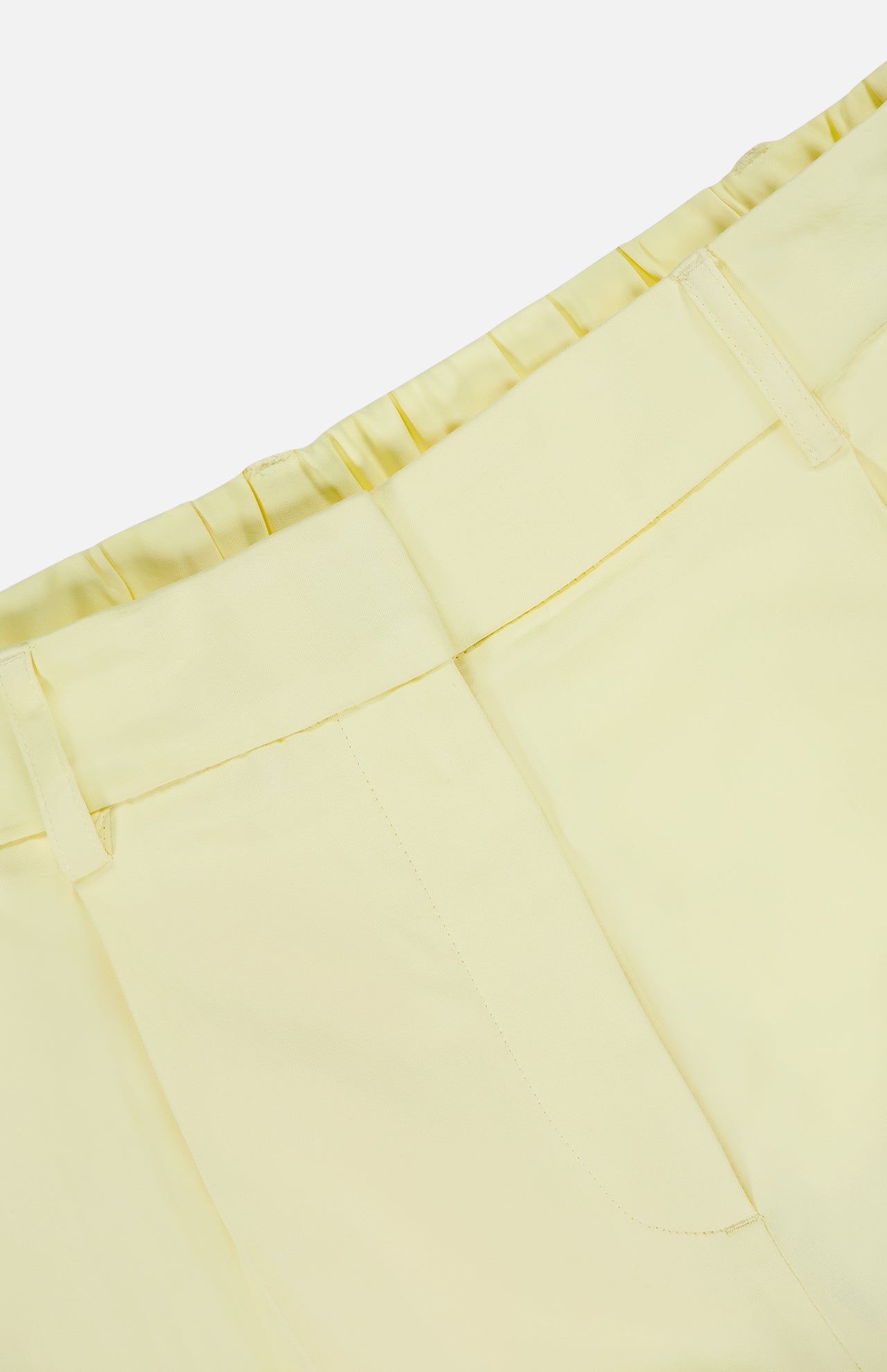 Close-up of the TWP Hudson St Pleated Pant in pale yellow, featuring belt loops, a pleated elastic back waistband, and front seam details—an ideal workwear choice for women.