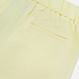 Close-up of the back of TWP’s Hudson St Pleated Pant in light yellow, designed for women with an elastic waistband and a single right welt pocket. The smooth, slightly shiny fabric makes it ideal workwear.