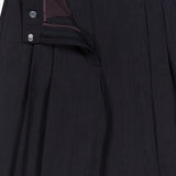 The Ivy Pleated Trouser Pant by TWP features dark Italian wool with elegant pleats, partially unzipped to reveal the refined waistband, button, and inner lining—expertly crafted as sophisticated mid rise workwear for women.