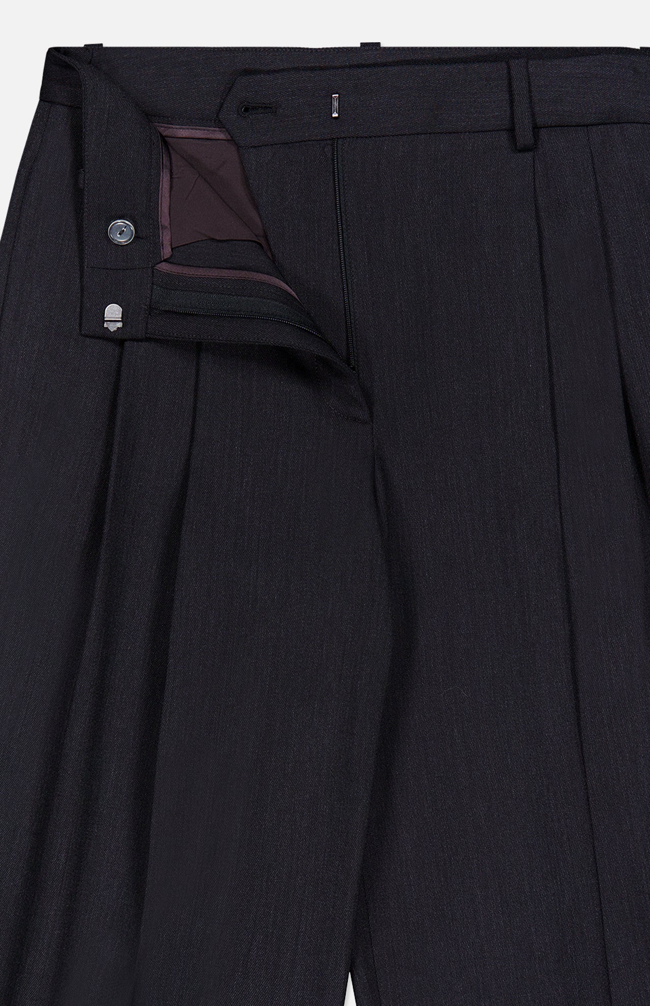 The Ivy Pleated Trouser Pant by TWP features dark Italian wool with elegant pleats, partially unzipped to reveal the refined waistband, button, and inner lining—expertly crafted as sophisticated mid rise workwear for women.