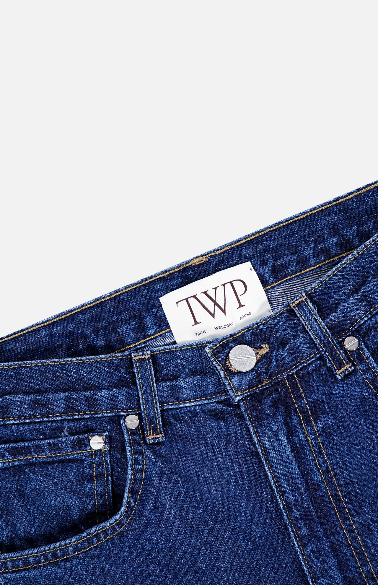 Close-up of the Kent St Jean in Dark Stone by TWP, showcasing a white label with bold TWP lettering on the inside of the waistband. The classic straight leg style features visible front pockets, belt loops, and metal rivet accents.