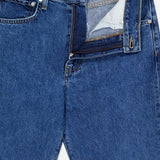 The Kent St Jean in Paris by TWP is a pair of blue jeans with a classic 5-pocket design and straight leg silhouette, featuring a partially unzipped fly that reveals the inner fabric and a waistband label marked with the TWP brand.
