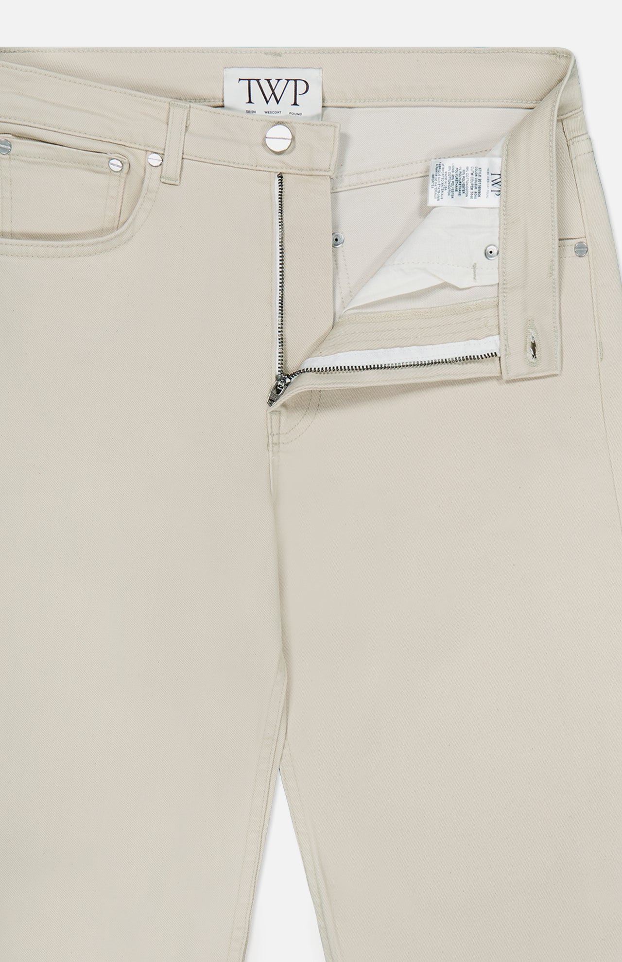 A pair of Kent St Pant in Bone by TWP, these mid-rise women’s straight-leg jeans feature a classic five-pocket design, with the front zipper and button partially open to reveal the inner label and waistband tag reading TWP.