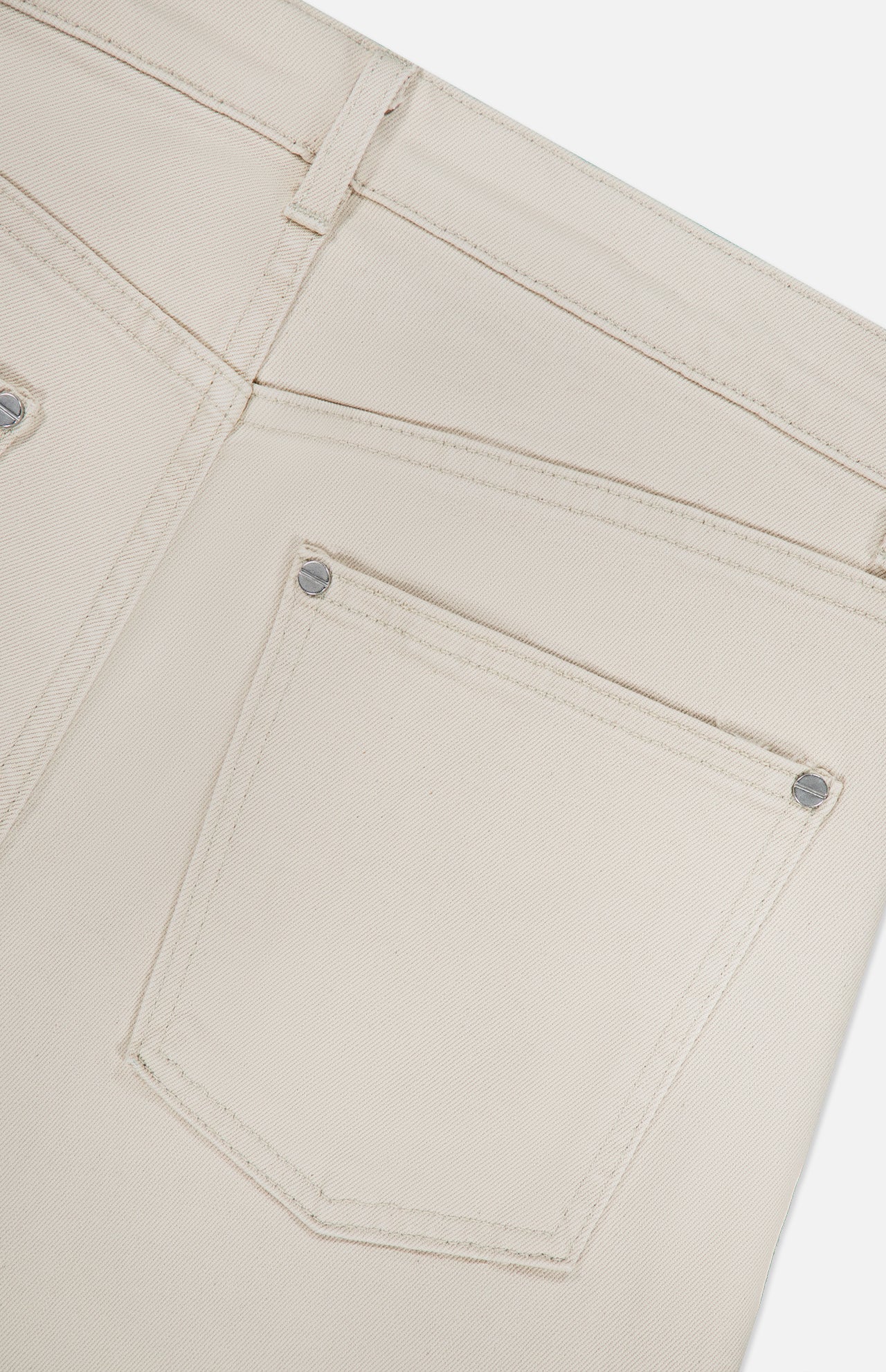 Close-up of the back pocket and waistband of the TWP Kent St Pant in Bone, highlighting stitching details and metal rivets against a plain white background.