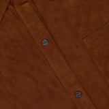 Close-up of the TWP Little Big Joe Jacket—a brown suede shirt jacket for women featuring black snap buttons, a chest pocket, and a partially visible collar label—an elevated reinterpretation of classic workwear.