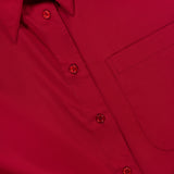 Close-up of the New Earl Wrap Front Dress by TWP: bright red with a breast pocket, red buttons, and pointed collar—ideal women’s workwear. A partially visible clothing label appears inside the collar.