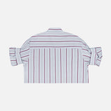 A back view of the TWP Next Ex Striped Blouse—a cropped, boxy white button-up shirt with vertical red and blue stripes and rolled-up sleeves—laid flat on a plain white background, presenting a stylish workwear option for women.