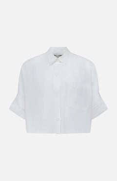 The TWP Next Ex Shirt in Linen is a white, cropped, boxy women's shirt with short sleeves, a collar, front pocket, and cuffs—perfect for workwear and shown against a plain background.
