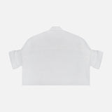 The TWP Next Ex Shirt in Linen is a white, cropped, boxy shirt with rolled-up sleeves and a minimal design—ideal for women’s workwear—shown from the back against a white background.