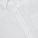 Close-up of the TWP Next Ex Cropped Stripe Shirt, featuring subtle vertical pinstripes, white buttons, and a right-side pocket—an elegant women's workwear choice. The collar and clothing label are visible at the top left.