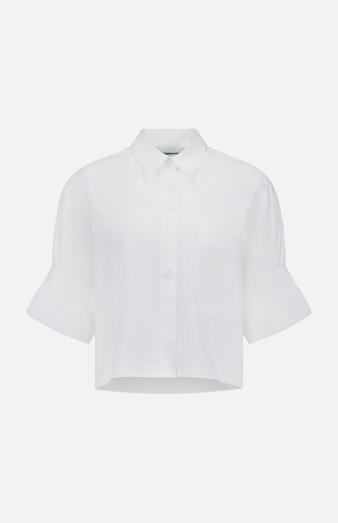 The TWP Next Ex Cropped Shirt is a boxy white top with short sleeves, classic collar, and cuffed details—an ideal workwear choice for women seeking a modern twist on timeless style. Displayed on a plain, light background.