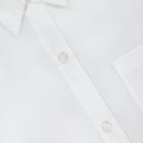 Close-up of the Next Ex Cropped Shirt by TWP—a crisp white, boxy-fit shirt with a pointed collar, chest pocket, and two white buttons. The label reads TWP in black, offering modern elegance for women’s workwear.