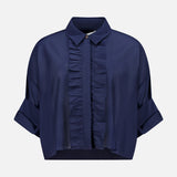 The TWP Next Ex Ruffle Blouse is a dark blue, short-sleeve button-up with a collared neckline, front ruffles, rolled cuffs, and a cropped boxy fit—ideal workwear for women. Shown against a plain white background.