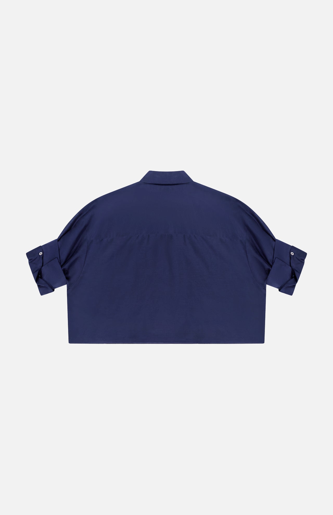 The TWP Next Ex Ruffle Blouse is a navy blue, short-sleeve collared cropped shirt with a relaxed fit and button-tab rolled sleeves—ideal workwear for women who value comfort and style. Shown from the back.